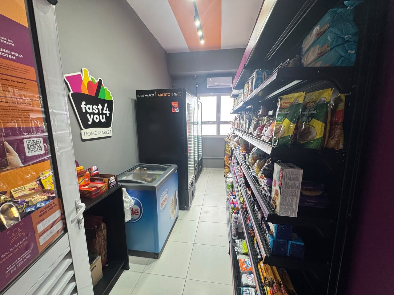 Interior do mercado 24h do condomínio, com freezer e prateleiras