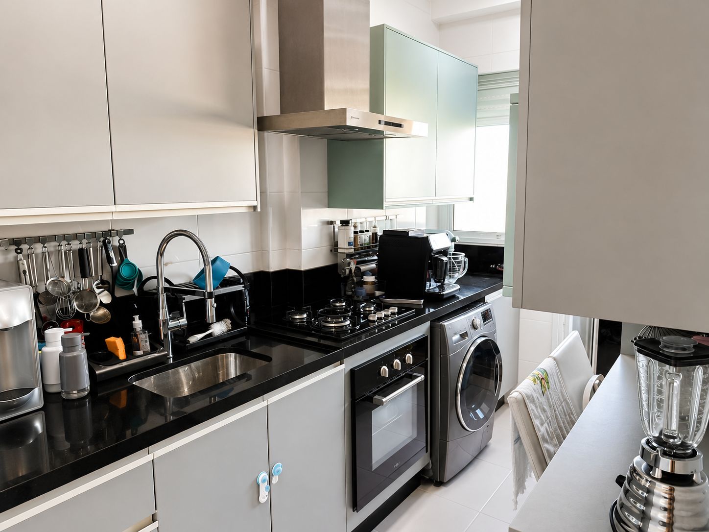Cozinha com bancada preta, cooktop e lavadora