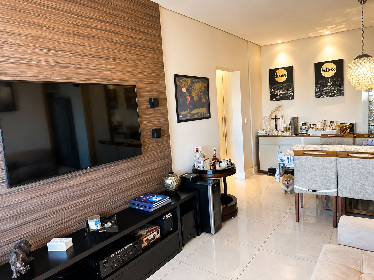 Sala com painel de madeira para a TV e mesa de jantar ao fundo